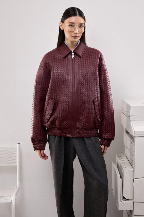 A woman wears a relaxed-fit burgundy bomber jacket with side pockets, offering a chic and modern look perfect for everyday wear.