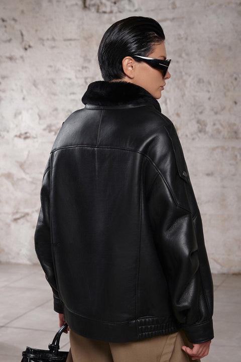 A woman dressed in a high-neck, oversized sheepskin jacket lined with soft shearling, showcasing a refined yet casual look ideal for cool weather layering.