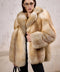 A woman dressed in a luxurious full pelt gold fox fur coat, perfect for Arctic temperatures, styled with sleek sunglasses for a striking, high-fashion winter look.