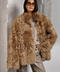 A woman wears an elegant ecru shearling coat with a soft, textured finish, exuding cozy luxury in cool weather.
