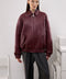 A woman wears a relaxed-fit burgundy bomber jacket with side pockets, offering a chic and modern look perfect for everyday wear.