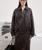 A woman models a deep brown bomber jacket designed for effortless layering, showcasing a relaxed fit and chic silhouette perfect for daily wear.