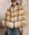 A woman wears a luxurious Gold Fox Fur Coat paired with jeans, showcasing a striking blend of fiery natural hues and casual elegance.